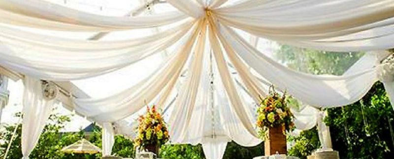 Outdoor canopy with white drapes and floral pillars