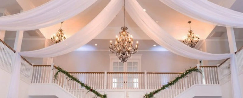 White tent ceiling with hanging drapes and chandeliers