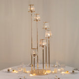 Elegant gold candle holder centerpiece with glass shades on a dining table.