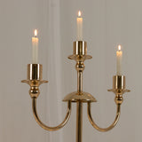 Gold candle holder with three lit candles.
