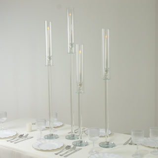 Elegant glass candle holders in varying heights on a table setting.