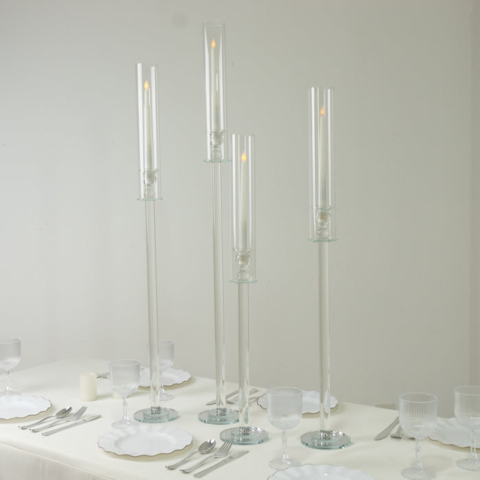 Elegant glass candle holders in varying heights on a table setting.