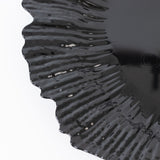 Black decorative plate with wavy edges on a plain background