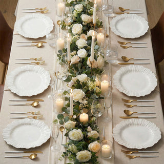 Elegant dining table set with white plates, gold utensils, and floral centerpiece.