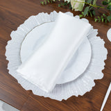 White satin napkin on a decorative plate with a ruffled edge.