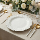 Elegant white decorative plate with gold utensils on a beautifully set dining table.