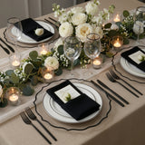 Elegant dining table setting with white roses, candles, and chic tableware.