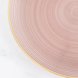 Pink ribbed plate with gold rim on a light background.