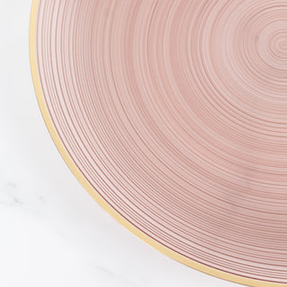 Pink ribbed plate with gold rim on a light background.