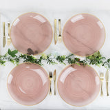 Elegant pink dining plates arranged with gold utensils and greenery accents.