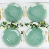 Green swirl dinner plates with gold rim and elegant cutlery set on a marble table.
