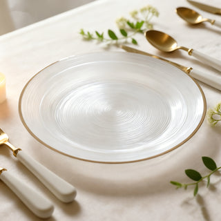 Elegant white plate with gold rim, surrounded by gold utensils and greenery.