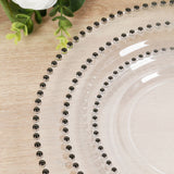 Clear plate with black beaded rim on a wooden surface.