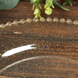 Clear plate with gold glitter design on wooden surface.