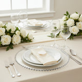 Elegant dining setup with white roses, plates, and glassware.