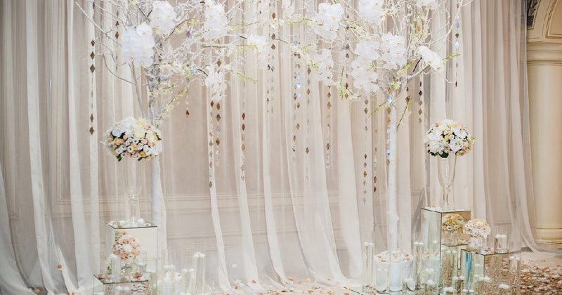 White floral wedding arch with sheer draping