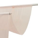Sheer beige curtains hanging on a metal curtain rod