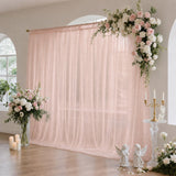 Blush pink wedding backdrop with floral arrangements and candles