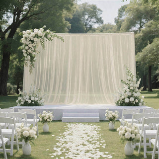 Elegant outdoor wedding ceremony setup with white flowers and draped backdrop