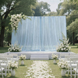 Outdoor wedding ceremony setup with blue drapery, white florals, and chairs