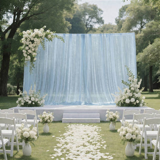 Outdoor wedding ceremony setup with blue drapery, white florals, and chairs
