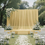 Elegant outdoor wedding ceremony with yellow draped stage and white floral decor