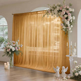 Elegant wedding floral arch with golden draped backdrop and candles