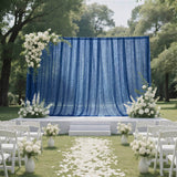 Outdoor wedding ceremony stage with blue drapes, white flowers, and chairs