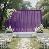 Outdoor wedding ceremony setup with purple drapery and white floral decor