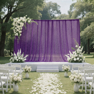 Outdoor wedding ceremony setup with purple drapery and white floral decor