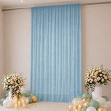 Blue sheer event curtain with floral arrangements, balloons, and candles