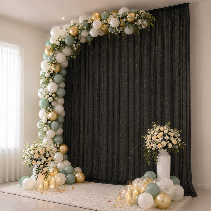 Elegant balloon arch with floral arrangements and candles on a black backdrop.