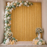 Elegant gold and sage balloon arch with floral decor and candles on a party backdrop
