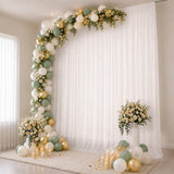 Elegant balloon and floral wedding backdrop with candles and draped white curtains