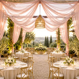 Elegant outdoor wedding reception with pink drapes, string lights, and scenic views