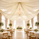 Elegant wedding reception with draped ceiling, chandelier, and floral table décor