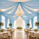 Elegant blue draped wedding reception with chandelier and floral tablescape