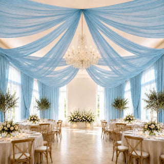 Elegant blue draped wedding reception with chandelier and floral tablescape