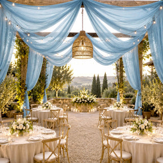 Elegant outdoor wedding reception with blue drapes, fairy lights, and floral tablescape