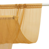 Sheer gold curtain panel hanging on a rod, close-up view