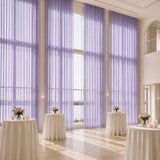 Elegant wedding reception hall with lavender drapes and cocktail tables by large windows