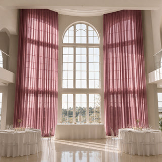 Elegant wedding reception with tall arched windows and pink drapes