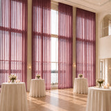 Elegant wedding reception with tall purple drapes and floral cocktail tables
