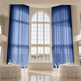 Elegant event hall with blue curtains, arched window, and round dining tables
