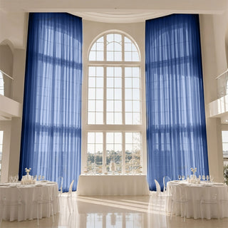 Elegant event hall with blue curtains, arched window, and round dining tables