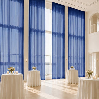 Elegant event hall with blue sheer drapes, cocktail tables, and waterfront view