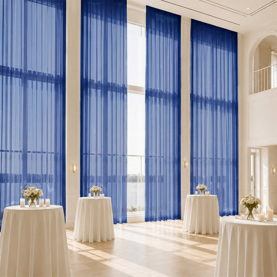 Elegant event hall with blue sheer drapes, cocktail tables, and waterfront view