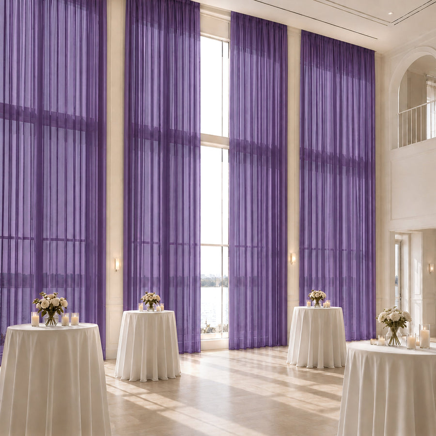 Elegant event venue with purple sheer curtains and white cocktail tables