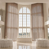 Elegant wedding reception hall with tall arched window and sheer drapes