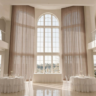 Elegant wedding reception hall with tall arched window and sheer drapes